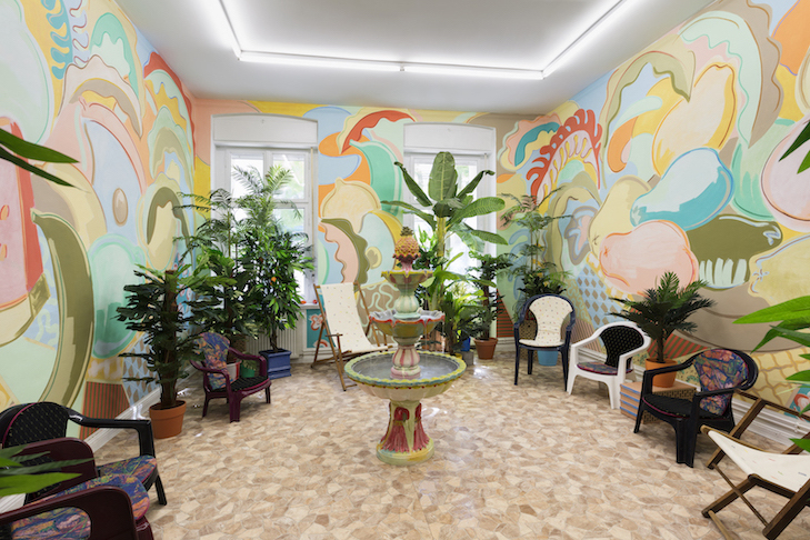 Sol Calero El patio de Espino, 2019 Acrylic and pastel on wall, plastic plants, chairs, bricks, vinyl floor, fountain Dimensions variable // Courtesy the artist and ChertLüdde, Berlin